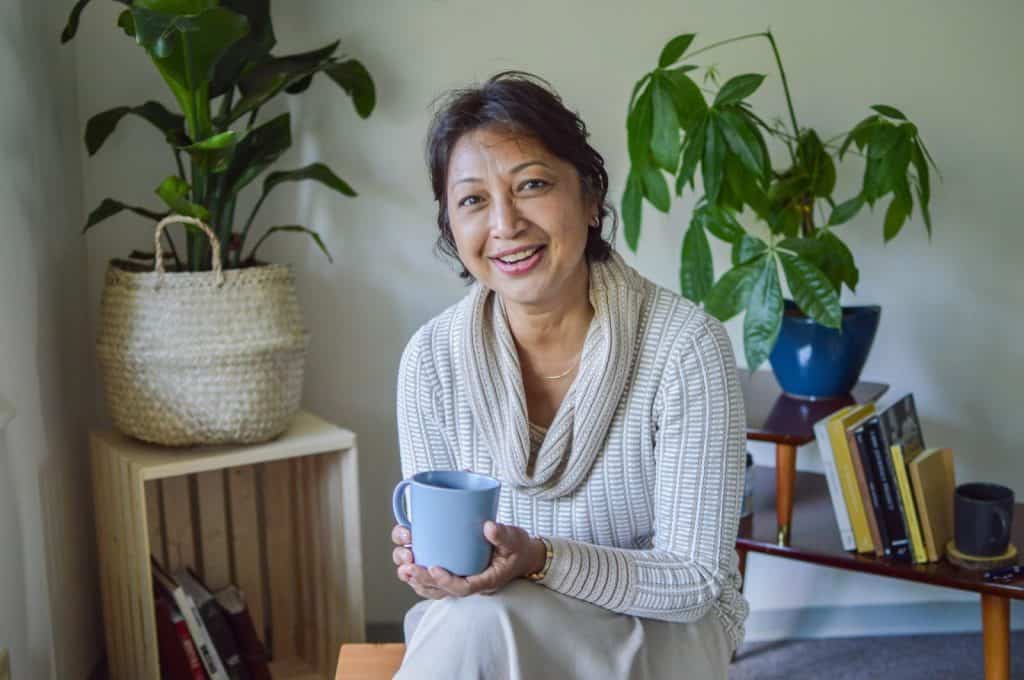 Karen holding a coffee mug and smiling.